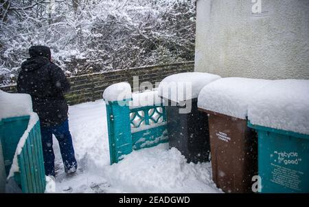 Glasgow, Écosse, Royaume-Uni. 9 février 2021. Sur la photo : une personne déverse une neige empilée sur un chemin piétonnier avec une pelle à neige tandis que Storm Darcy a déposé près d'un pied de neige sur des chemins de nuit bloquant et se renversant sur les murs, les portes, les bennes à roues. La nuit précédente a également vu la neige tomber, mais pas autant que la nuit dernière. Les températures glaciales se sont maintenues autour de -1C, la nuit dernière étant la plus froide jusqu'à présent. Crédit : Colin Fisher/Alay Live News Banque D'Images