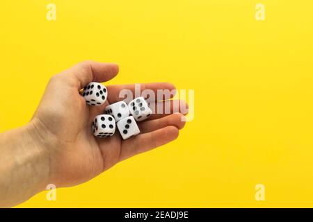 Femme main tenant cinq dés. Jouer à cube avec des nombres. Articles pour jeux de société. Arrière-plan jaune flou. Banque D'Images