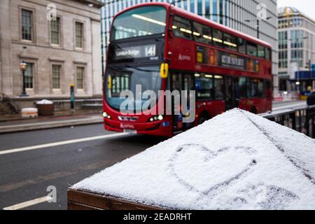 Signe d'amour en forme de coeur, dessiné sur une glace enneigée. Hiver à Londres, bus rouge. Toile de fond romantique. Forme d'un coeur sur la neige. Banque D'Images