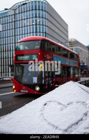 Signe d'amour en forme de coeur, dessiné sur une glace enneigée. Hiver à Londres, bus rouge. Toile de fond romantique. Forme d'un coeur sur la neige. Banque D'Images