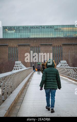 Une personne marche sur le Millennium Bridge lors d'une froide journée d'hiver avec de la neige à Londres. Banque D'Images