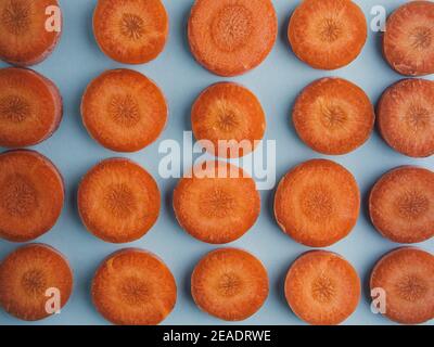 fond orange. gros plan de carottes en tranches circulaires sur fond bleu. Bouquet de carottes biologiques à l'orange. Légumes naturels que vous venez de récolter. Coloré Banque D'Images