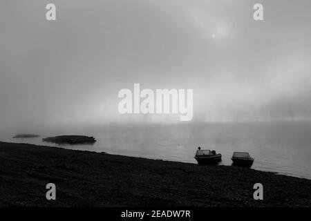 Brouillard matinal sur la rivière Lena, taïga de Sibérie. Bateaux de pêche sur la rive à l'aube brumeuse Banque D'Images