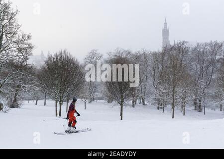 Les gens qui profitent de la neige d'hiver à Kelvingrove Park Glasgow, Royaume-Uni. Enfants en traîneau. Ski dans le parc. Cycliste. Tempête d'hiver. Université de Glasgow. Banque D'Images