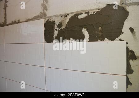 Installation de carreaux muraux en céramique blanche sur un mur en béton cellulaire autoclavé, surface de maçonnerie dans une salle de bains. Banque D'Images