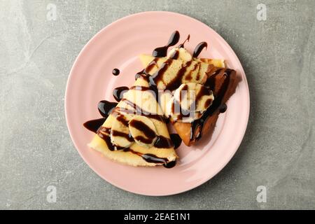 Assiette de crêpes avec sauce au chocolat et tranches de banane arrière-plan gris Banque D'Images