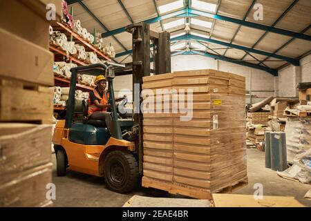 Opérateur de chariot élévateur africain mobile des boîtes autour d'un entrepôt Banque D'Images