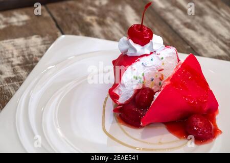 Gâteau froid à la crêpe aux fraises avec cerise dans un plat blanc sur une table en bois. Banque D'Images