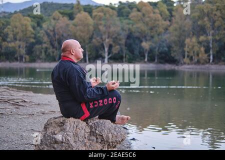 artiste martial méditant à un lac avec noir et rouge kimono Banque D'Images