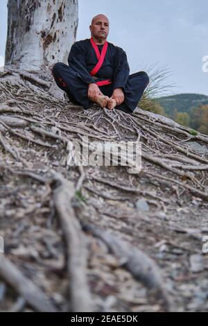 artiste martial méditant à un lac avec noir et rouge kimono Banque D'Images