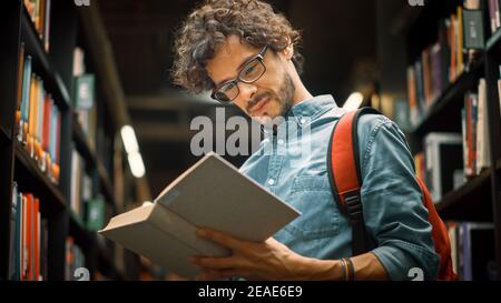 Bibliothèque de l'université : un garçon hispanique de talent portant des lunettes debout à côté de la bibliothèque lit le livre pour son affectation de classe et les préparatifs d'examen. Faible Banque D'Images