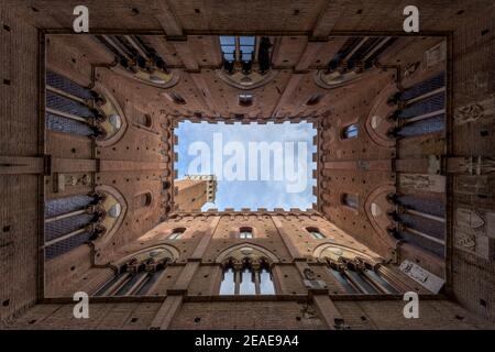 Vue verticale de bas en haut de la cour intérieure du Palazzo Pubblico, un bâtiment médiéval de l'hôtel de ville sur la place principale de la vieille ville de Sienne en Toscane, Banque D'Images