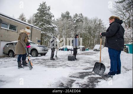 Glasgow, Écosse, Royaume-Uni. 9 février 2021. Photo : les gens déneigement et la glace compactée après que les petites routes ont été laissées à l'écart et qu'elles ont été labourées par le Conseil du Lanarkshire du Nord, comme après la tempête Darcy a déposé près d'un pied de neige sur des chemins de nuit bloquant et se déversant sur les murs, les portes, les bennes à roues. La nuit précédente a également vu la neige tomber, mais pas autant que la nuit dernière. Les températures glaciales se sont maintenues autour de -1C, la nuit dernière étant la plus froide jusqu'à présent. Crédit : Colin Fisher/Alay Live News Banque D'Images