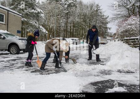 Glasgow, Écosse, Royaume-Uni. 9 février 2021. Photo : les gens déneigement et la glace compactée après que les petites routes ont été laissées à l'écart et qu'elles ont été labourées par le Conseil du Lanarkshire du Nord, comme après la tempête Darcy a déposé près d'un pied de neige sur des chemins de nuit bloquant et se déversant sur les murs, les portes, les bennes à roues. La nuit précédente a également vu la neige tomber, mais pas autant que la nuit dernière. Les températures glaciales se sont maintenues autour de -1C, la nuit dernière étant la plus froide jusqu'à présent. Crédit : Colin Fisher/Alay Live News Banque D'Images