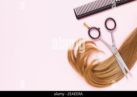 Ciseaux, un peigne et un fil coupé de cheveux de femme de couleur claire pour enfants avec un espace de copie sur fond rose. Services de coiffure. Banque D'Images