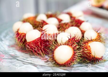 L'écorce de rambutan est coupée en deux sur un plat en verre et prête à manger. Banque D'Images