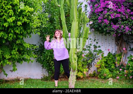 la femme montre les mains derrière un grand cactus, des fleurs d'arbre Banque D'Images