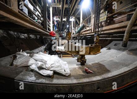 (210209) -- ZHONGNING, 9 février 2021 (Xinhua) -- UN travailleur assemble des lignes de chemin à l'intérieur d'un tunnel traversant la rivière jaune dans le comté de Zhongning, Zhongwei ville du nord-ouest de la Chine Ningxia hui Autonomous Reigon, 9 février 2021. Plus de 100 travailleurs sont encore en service dans le tunnel pour assurer le développement du projet à temps malgré le prochain Festival du printemps, ou le nouvel an lunaire chinois. Ce tunnel, le deuxième à traverser la rivière jaune à Ningxia, s'inscrit dans le cadre d'un plus grand projet visant à fournir un service de chauffage aux résidents de Zhongning. (Xinhua/Feng Kaihua) Banque D'Images
