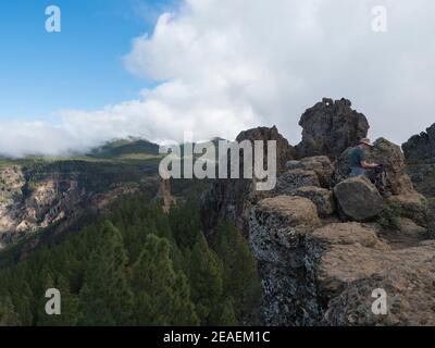 Cruz de Tejeda, Îles Canaries, Espagne 15 décembre 2020 : homme aîné se reposant sur un sentier de randonnée au parc Roque Nublo, dans les montagnes centrales intérieures avec du vert Banque D'Images