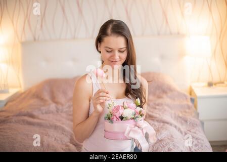 Jeune femme dans un lit rose avec fleurs - cadeau pour Février 14 ou mars 8 Banque D'Images