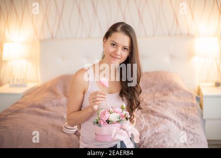 Jeune femme dans un lit rose avec fleurs - cadeau pour Février 14 ou mars 8 Banque D'Images