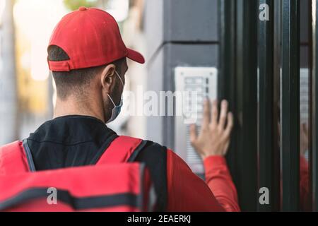 Homme pilote qui fournit des repas à la maison des clients tout en portant le visage Masque pendant l'épidémie de virus corona - concept de la livraison de nourriture Banque D'Images