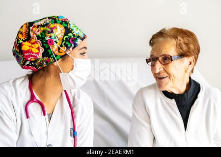 Femme âgée souriant en parlant à l'infirmière qui est prenant soin d'elle Banque D'Images