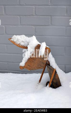 chien décoratif en métal rouillé dans la neige et le mur peint en gris arrière-plan Banque D'Images