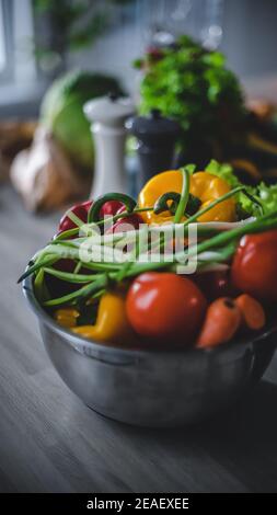 Gros plan d'un bol gris plein de légumes frais et sains sur une table de cuisine. Produits naturels propres préparés pour la salade : doux jaune Banque D'Images