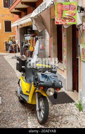 Piaggio Liberty scooter dans la poste Italiane S.p.A. livrée garée à l'extérieur d'un magasin à Malcesine, Lac de Garde, Italie. Banque D'Images