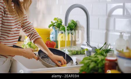 Gros plan photo d'une femme lavant une poêle avec un liquide de nettoyage sous l'eau du robinet. Utilisation du lave-vaisselle dans une cuisine moderne. Régime naturel propre et Banque D'Images