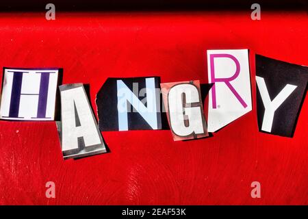 TheWord 'Hangry' en utilisant des lettres papier découpées dans la note de rançon Appliquer la typographie sur un arrière-plan rouge Banque D'Images