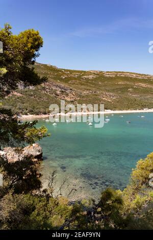 Plage de Portinho da Arrabida avec bateaux ancrés dans l'eau cristalline Banque D'Images