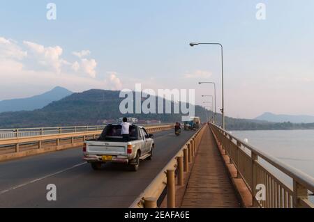 Pakse, Laos - avril 2015 : un jeune garçon conduit dans une aire de chargement ouverte d'un camion de ramassage sur un pont traversant le Mékong. Pont appelé pont Lao-Nippon Banque D'Images