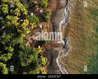 Guadeloupe plage vue sur le coucher du soleil. Plage Caraibe vue aérienne de la plage noire à Pointe Noire. Ombres à vagues de l'océan rétroéclairées. Banque D'Images