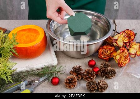 Comment faire une décoration de Noël durable faite de roses séchées, brindilles de sapin et de boules. Arrangement floral à l'intérieur de la citrouille. Étape par étape, tuto Banque D'Images