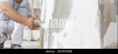 Mains homme plâtrier ouvrier de construction au travail avec truelle, plâtrage d'un mur, gros plan Banque D'Images