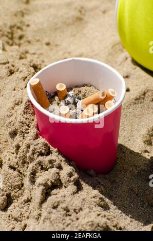 Cigarettes non allumées dans un verre à plomb sur la plage Banque D'Images