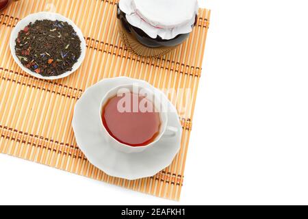 Tasse de thé, confiture et feuilles de thé isolées sur fond blanc. Flat lay, vue de dessus. Espace libre pour le texte. Banque D'Images