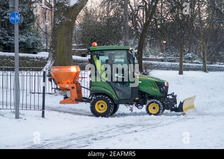 Un homme qui conduit un tracteur répandant du sel le long du parc Meadows dans le centre-ville d'Édimbourg. Banque D'Images