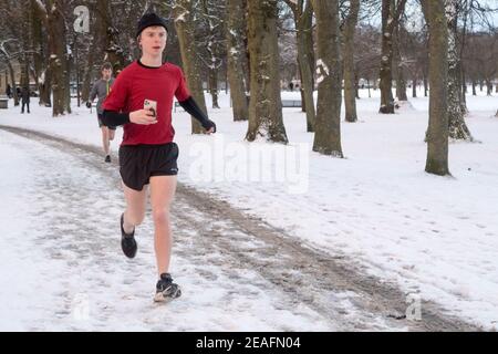 Un homme qui court dans un parc couvert de neige les premières heures du matin Banque D'Images