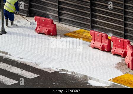 Travailleur de la construction travaillant avec du béton blanc sur un trottoir en réparation. Concept d'entretien urbain Banque D'Images