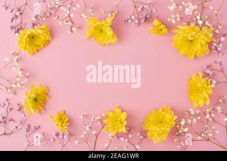 Concept de Pâques. Œufs et chrysanthèmes jaunes fleurs sur fond rose. Maquette. Carte de vacances joyeuses Pâques du printemps. Vue de dessus. Banque D'Images