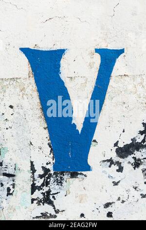 Lettre V bleue peinte sur un mur qui s'écaille Banque D'Images