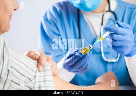 Médecin GP femelle tenant flacon ampoule avec liquide jaune, seringue de remplissage Avec injection par injection, vaccine des patients âgés, coronavirus COVID-19 virus Banque D'Images