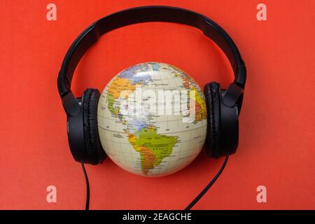 Micro-casque sur globe isolé sur le rouge Banque D'Images