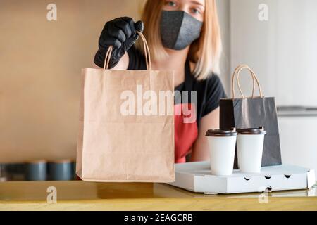 Sac alimentaire, pizza, forfait boisson à emporter au restaurant à emporter. Le travailleur de cuisine émet des commandes en ligne dans des gants et un masque. Maquette de sac en papier à emporter Banque D'Images