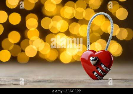 Concept de la Saint-Valentin. Cadenas en forme de coeur sur une table rustique en bois devant un arrière-plan lumineux flou avec espace pour le texte. Sélectif f Banque D'Images