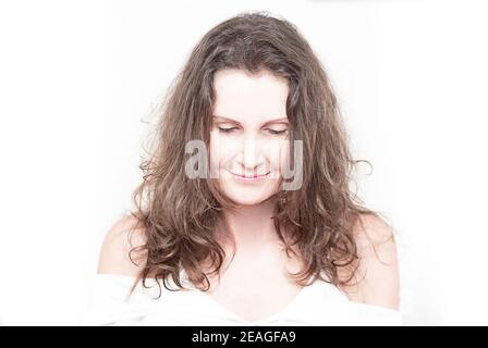 Portrait d'une femme caucasienne avec de longs cheveux bruns foncés sur fond blanc. Photo d'été surexposée. Banque D'Images