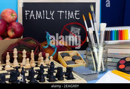 Un moment de famille avec un symbole gratuit sur la table avec jeux, matériel d'art et d'artisanat et livres. Encourager les temps d'arrêt numériques à renouer avec la famille Banque D'Images